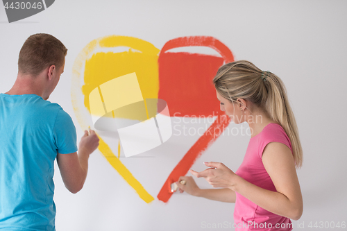 Image of couple are painting a heart on the wall