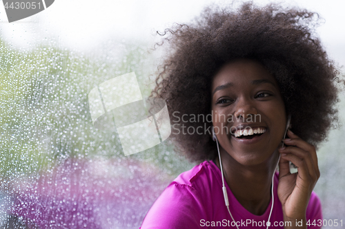 Image of portrait of young afro american woman in gym while listening mus