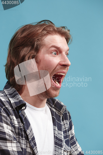 Image of The young emotional angry man screaming on blue studio background