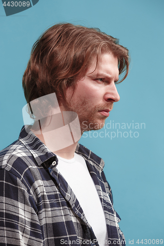 Image of The serious business man standing and looking at camera against blue background.