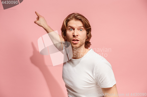 Image of Beautiful male half-length portrait isolated on pink studio backgroud. The young emotional surprised man