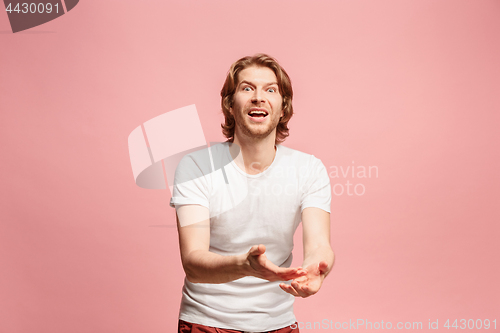 Image of Beautiful male half-length portrait isolated on pink studio backgroud. The young emotional surprised man