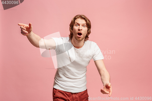 Image of Beautiful male half-length portrait isolated on pink studio backgroud. The young emotional surprised man