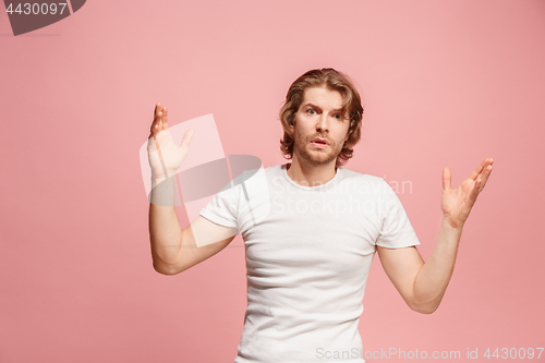 Image of Beautiful male half-length portrait isolated on pink studio backgroud. The young emotional surprised man