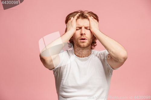 Image of man having headache. Isolated over pink background.