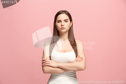 Image of The serious business woman standing and looking at camera against pink background.