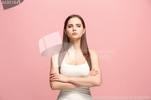 Image of The serious business woman standing and looking at camera against pink background.