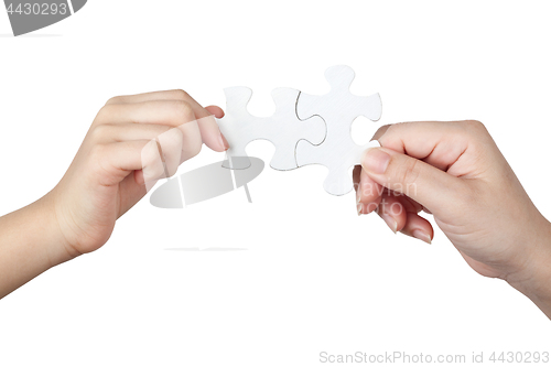 Image of Female and child hand holding jigsaw puzzle pieces