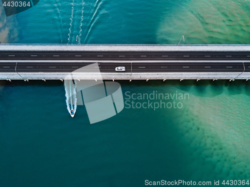 Image of Car crosses bridge as speed boat travels under it. Aerial view