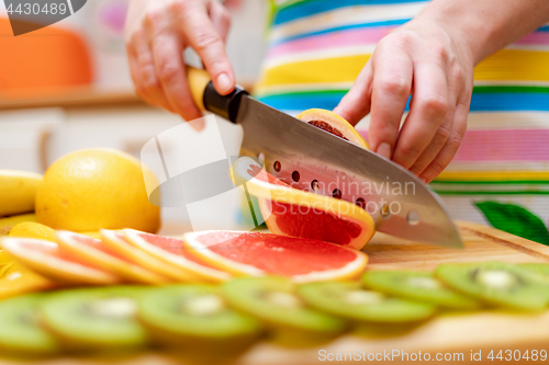 Image of Women\'s hands Housewives cut with a knife fresh grapefruit on th