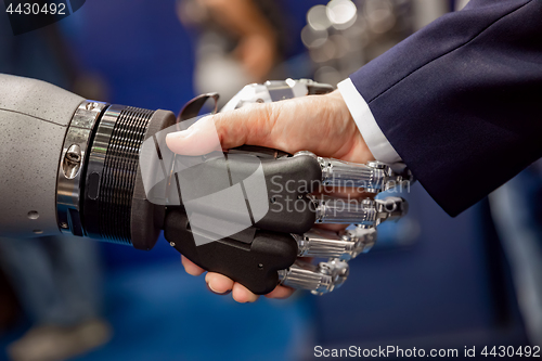 Image of Hand of a businessman shaking hands with a Android robot.