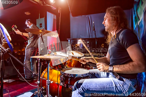 Image of Drummer playing on drum set on stage.