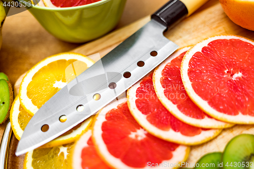 Image of Sharp kitchen knife on cutting Board next to sliced grapefruit a