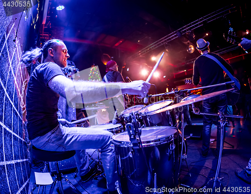 Image of Drummer playing on drum set on stage.