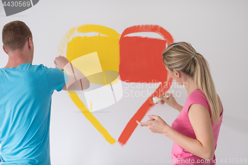 Image of couple are painting a heart on the wall