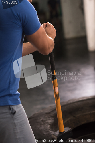 Image of man workout with hammer and tractor tire