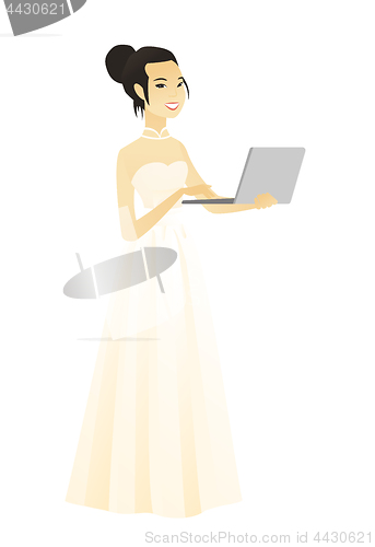 Image of Asian bride in a white dress using a laptop.