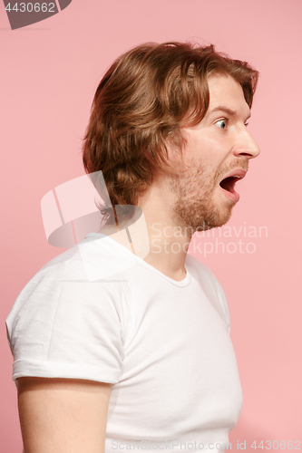 Image of The young attractive man looking suprised isolated on pink