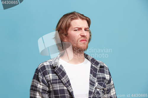 Image of Let me think. Doubtful pensive man with thoughtful expression making choice against blue background