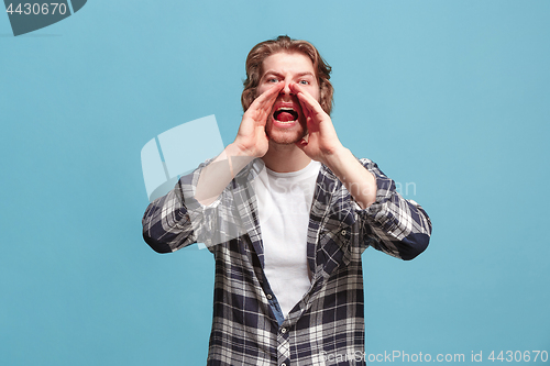 Image of Isolated on blue young casual man shouting at studio