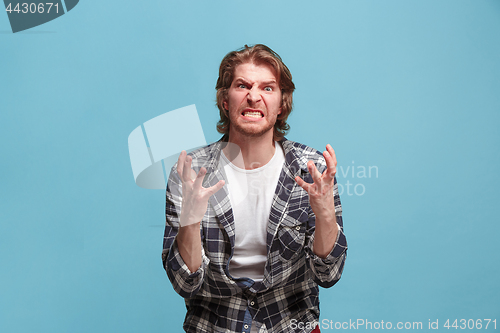 Image of Portrait of an angry man looking at camera isolated on a blue background