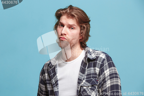 Image of Let me think. Doubtful pensive man with thoughtful expression making choice against blue background