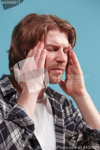 Image of man having headache. Isolated over blue background.