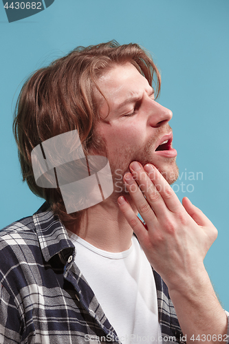 Image of The Ear ache. The sad man with headache or pain on a blue studio background.