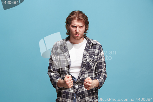 Image of Portrait of an angry man looking at camera isolated on a blue background