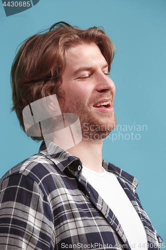 Image of The happy businessman standing and smiling against blue background.