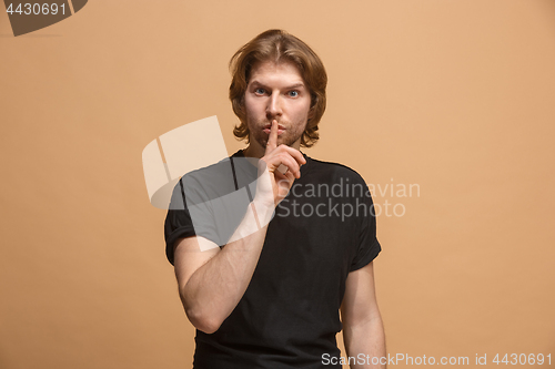 Image of The young man whispering a secret behind her hand over pastel background