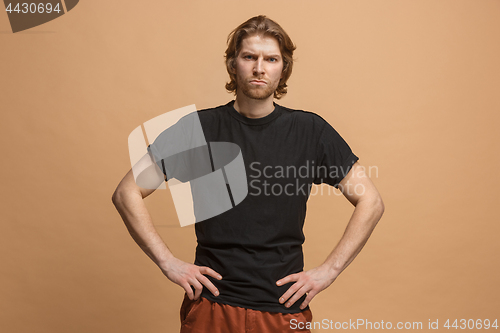 Image of The serious businessman standing and looking at camera against pastel background.