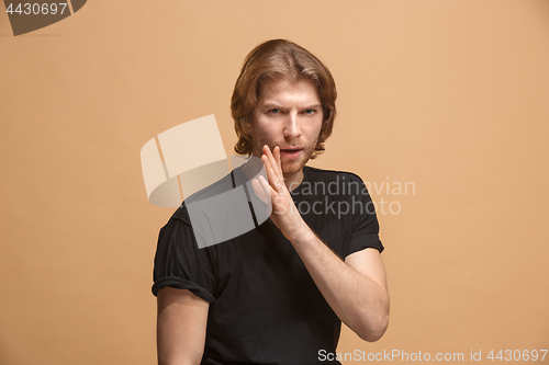 Image of The young man whispering a secret behind her hand over pastel background