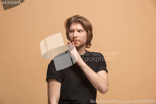 Image of The young man whispering a secret behind her hand over pastel background