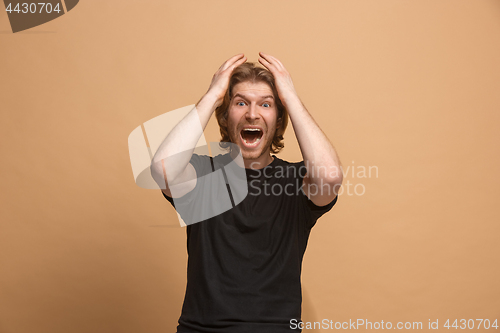 Image of The young attractive man looking suprised isolated on pastel