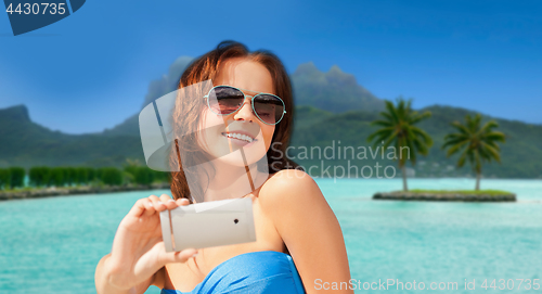 Image of woman taking selfie by smartphone on bora bora