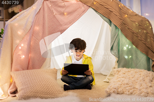 Image of little boy with tablet pc in kids tent at home