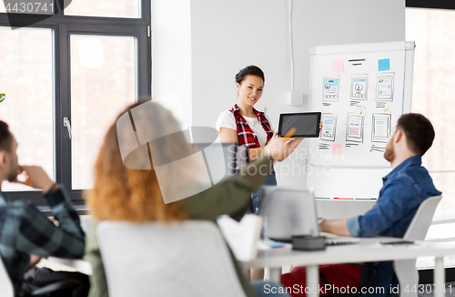 Image of woman showing tablet pc to creative team at office