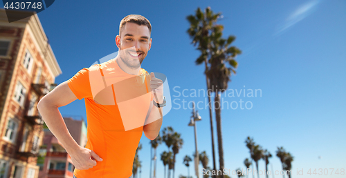 Image of smiling young man running at summer seaside