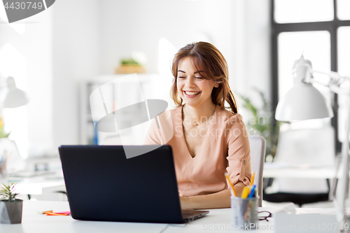 Image of happy businesswoman with laptop working at office