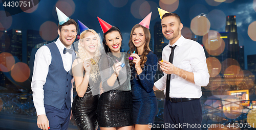 Image of happy friends with party blowers having fun