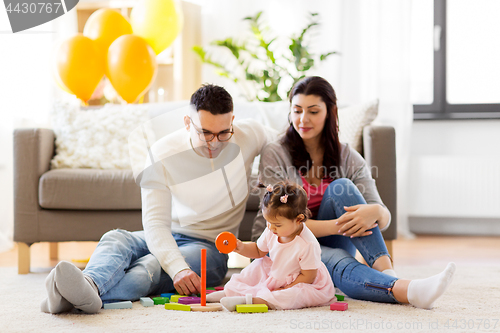 Image of baby girl with parents playing with pyramid toy