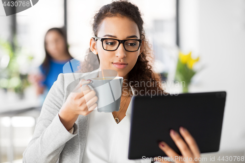 Image of businesswoman with tablet pc and coffee at office