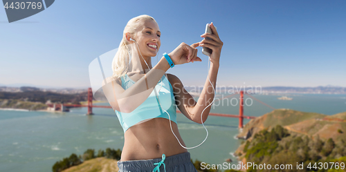 Image of woman with smartphone and earphones doing sports