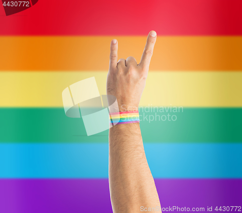 Image of hand with gay pride rainbow wristband shows rock