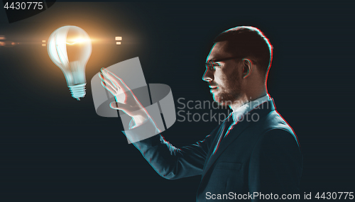 Image of businessman with virtual light bulb projection