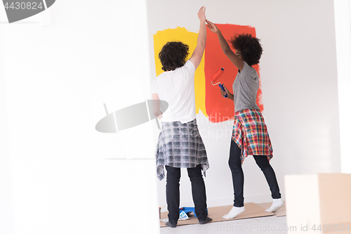 Image of multiethnic couple painting interior wall