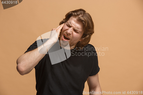 Image of The Ear ache. The sad man with headache or pain on a pastel studio background.