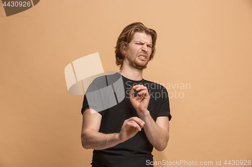 Image of Young man with disgusted expression repulsing something, isolated on the pastel