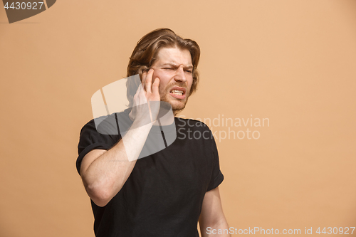 Image of The Ear ache. The sad man with headache or pain on a pastel studio background.